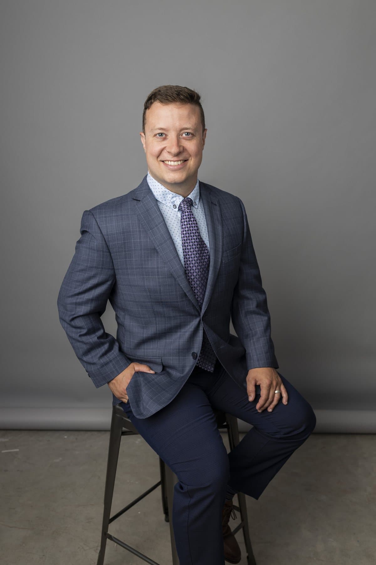 K. Joel Leonard, CFP®, seated on a stool, smiling
